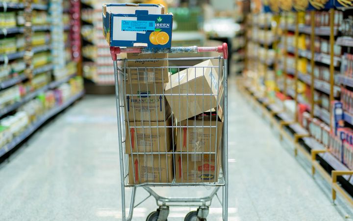 A shopping cart with packages in a grocery aisle, showcasing everyday shopping options.