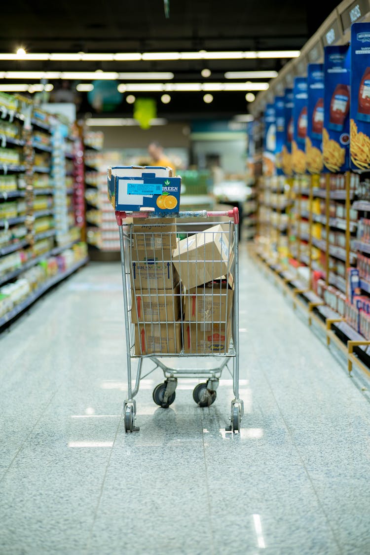 Shopping Cart Filled With Packages In Empty Aisle