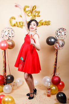 Woman in red dress celebrating birthday with balloons and champagne.