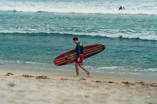 Surfer Walking on Beach on Sea Shore