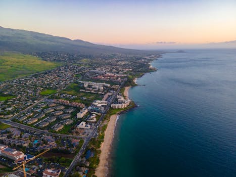 A breathtaking aerial view of Kihei, Hawaii, showcasing the coastline and vibrant community during a serene sunrise.