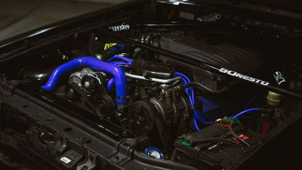 Detailed view of a car engine featuring vibrant blue pipes and machinery components.