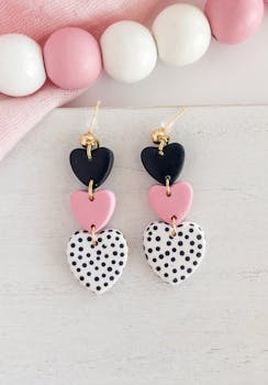 Chic heart-shaped earrings in black, pink, and polka-dot design on a white background.