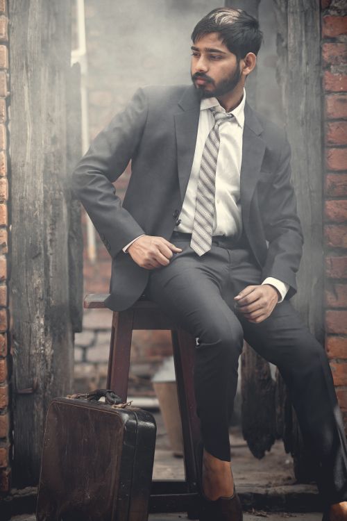 Free Sophisticated man in a suit with a beard sitting on a bar stool indoors, exuding elegance. Stock Photo