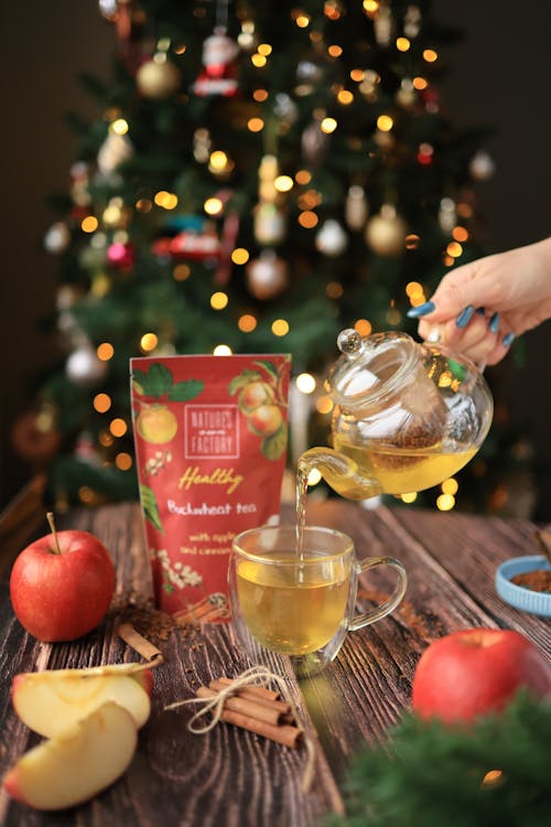 Woman Pouring Tea into a Glass on the Background of a Christmas Tree