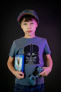 Portrait of a boy in a cap holding a video game controller and game case.