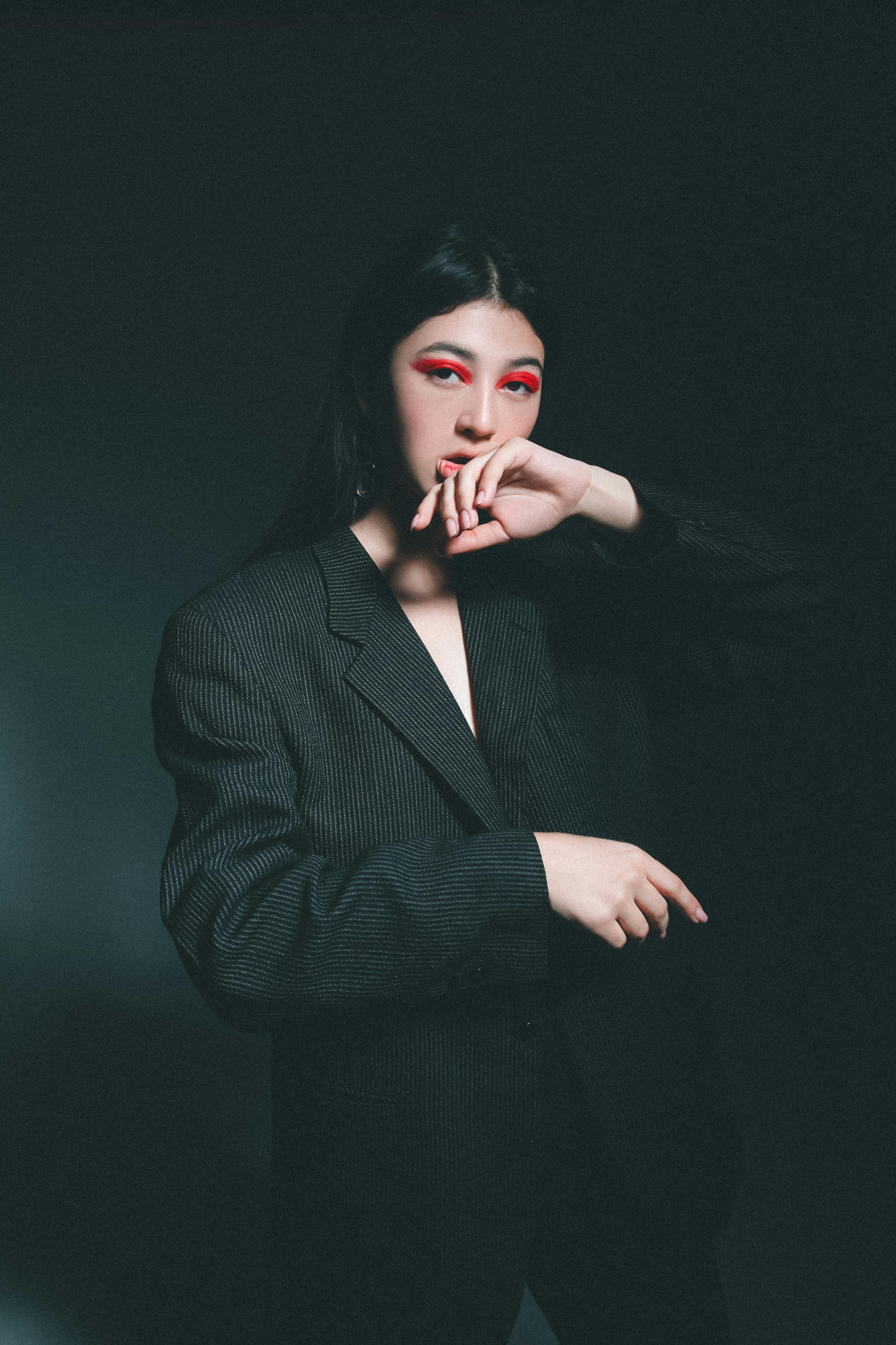 Studio portrait of a fashionable woman with striking makeup and a dark blazer.