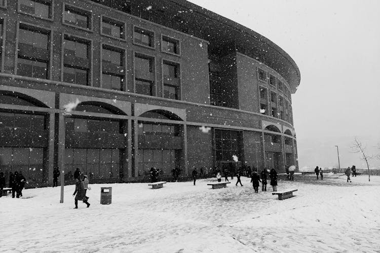 People Walking Near Building In Winter In Black And White