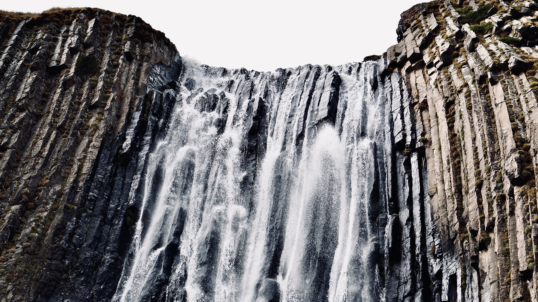 Dramatic waterfall flowing over striking basalt formations, showcasing nature's power.
