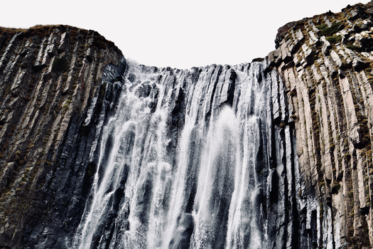 Dramatic waterfall flowing over striking basalt formations, showcasing nature's power.