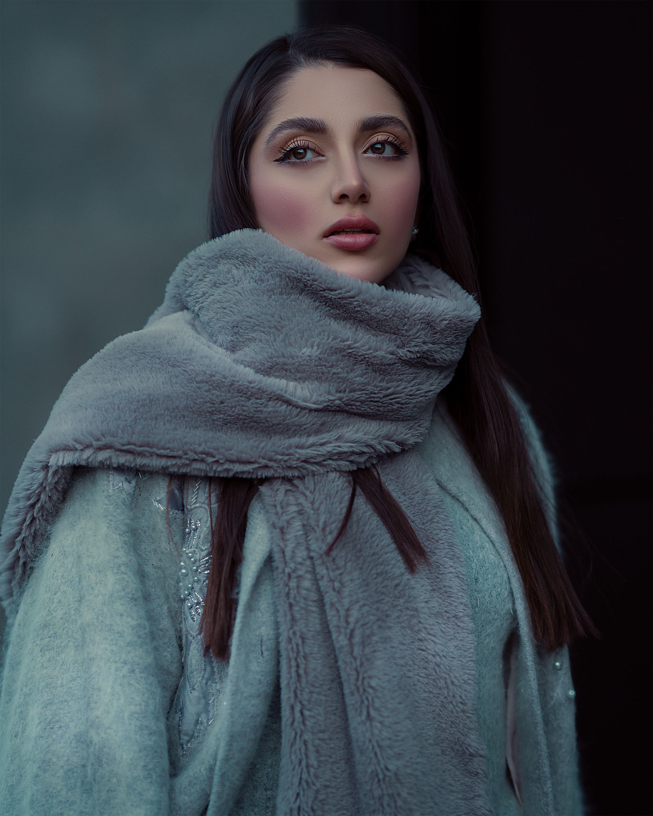 Sophisticated woman in gray scarf and coat, showcasing winter fashion elegance.