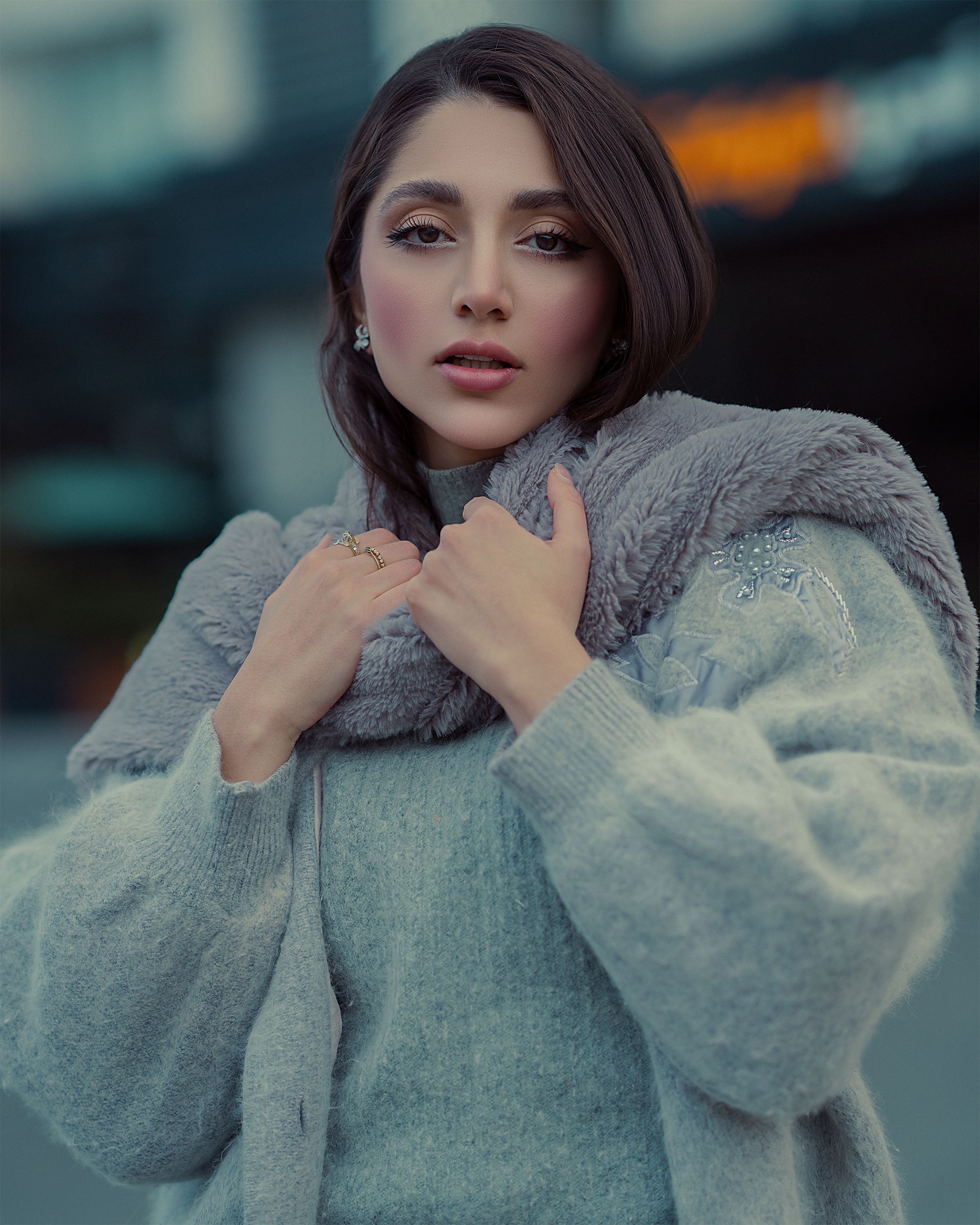 Chic woman in a winter coat and scarf, outdoors with a soft, cool tone aesthetic.