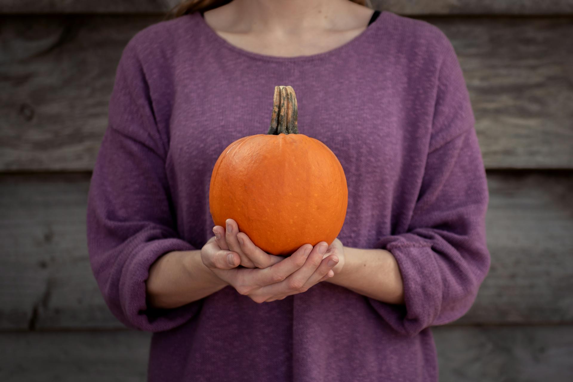 Photo of Woman Carrying Pumpkin on Both Hands