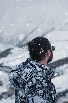Man in stylish jacket stands in Tehran during a snowy winter day.