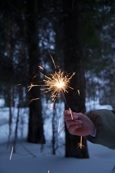 Sparkler illuminates a snowy forest, creating a vibrant winter celebration atmosphere.