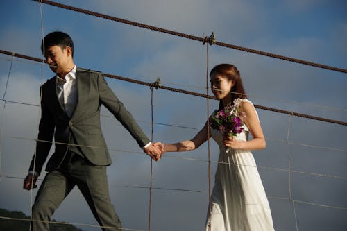 Bride and Groom Holding Hands and Walking on the Bridge 