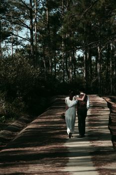 A couple in love walking arm in arm down a scenic forest path.