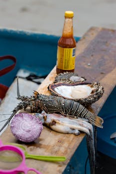 Close-up of fresh seafood including lobster, shellfish, and condiments on a wooden table.