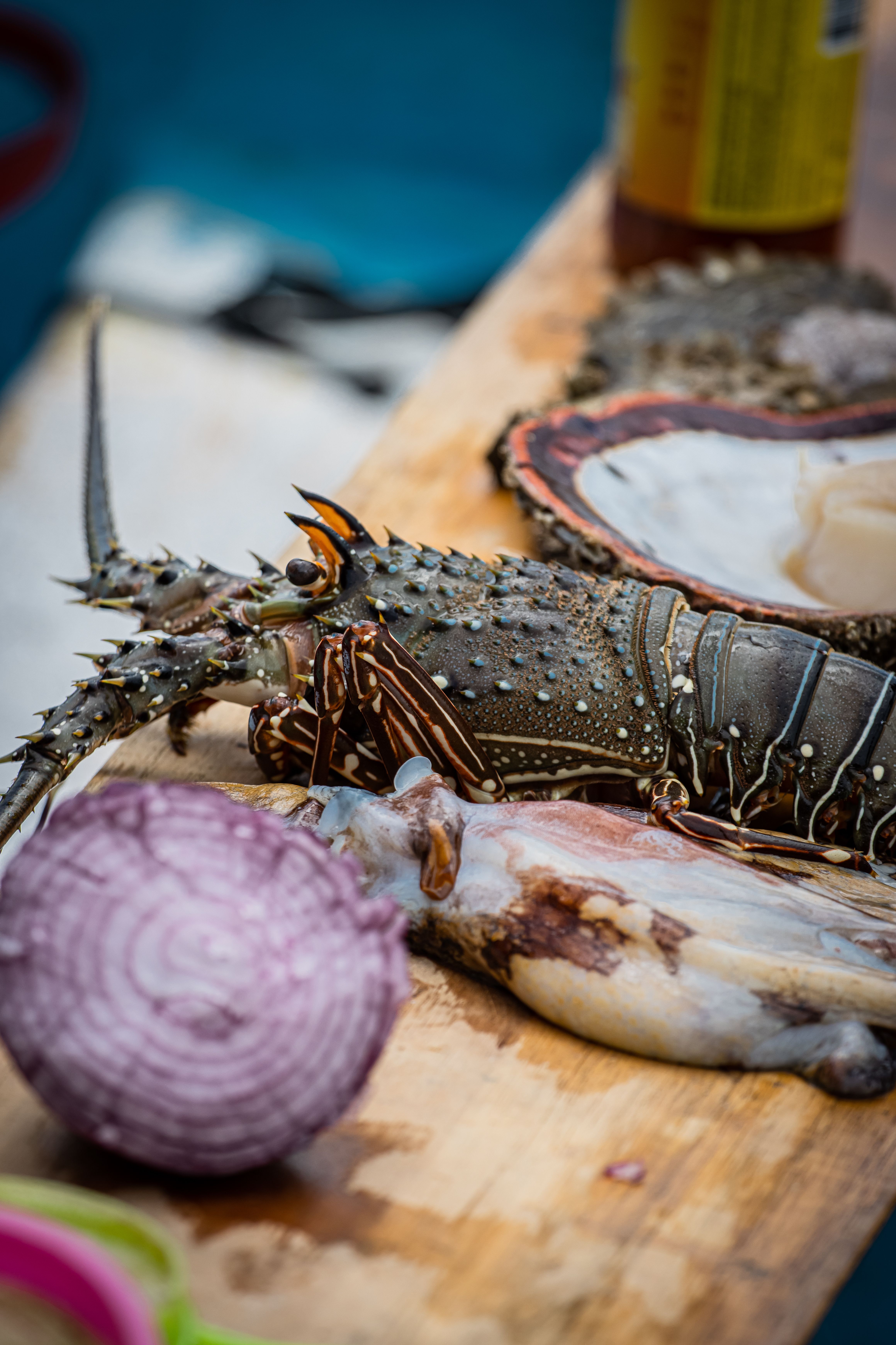 Close-up of fresh lobster and assorted seafood on a wooden cutting board, vibrant colors.