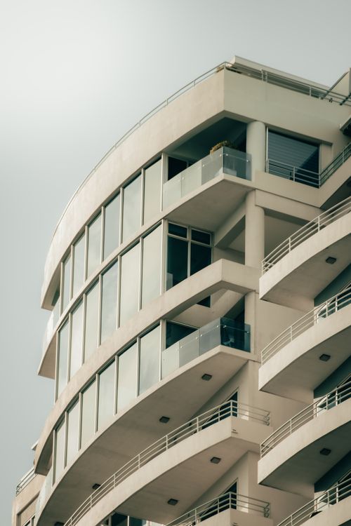 Free A modern residential building with a sleek, curved facade and large windows. Stock Photo