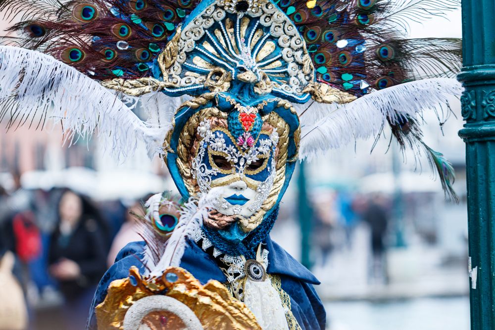 Mască venețiană ornamentată cu pene de păun, purtată la carnaval