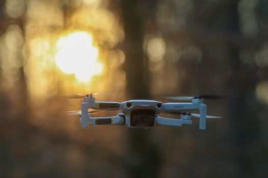A drone flying in a sunlit forest, highlighting modern aerial technology.
