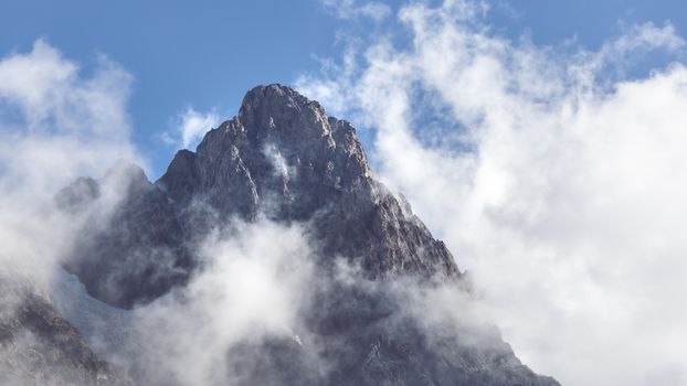 Stunning view of a mountain peak enveloped by clouds, showcasing nature's grandeur.