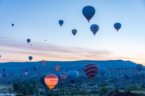 Free A stunning view of hot air balloons rising over Cappadocia's unique landscape at sunrise. Stock Photo