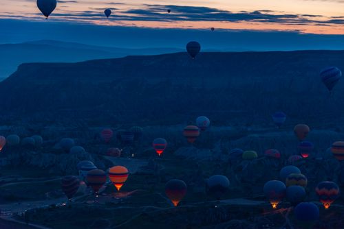 Free A stunning twilight scene of hot air balloons floating above the rocky terrain of Cappadocia. Stock Photo