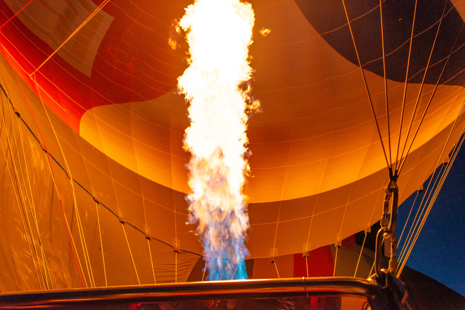 Close-up of a vibrant flame inflating a hot air balloon at night, showcasing dynamic lighting and colors.