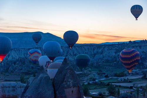 Free Colorful hot air balloons soar over Cappadocia's rock formations during a beautiful sunrise. Stock Photo