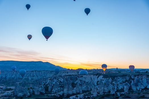 Hot air balloons float over Cappadocia's unique rock formations during sunrise, offering a breathtaking view.