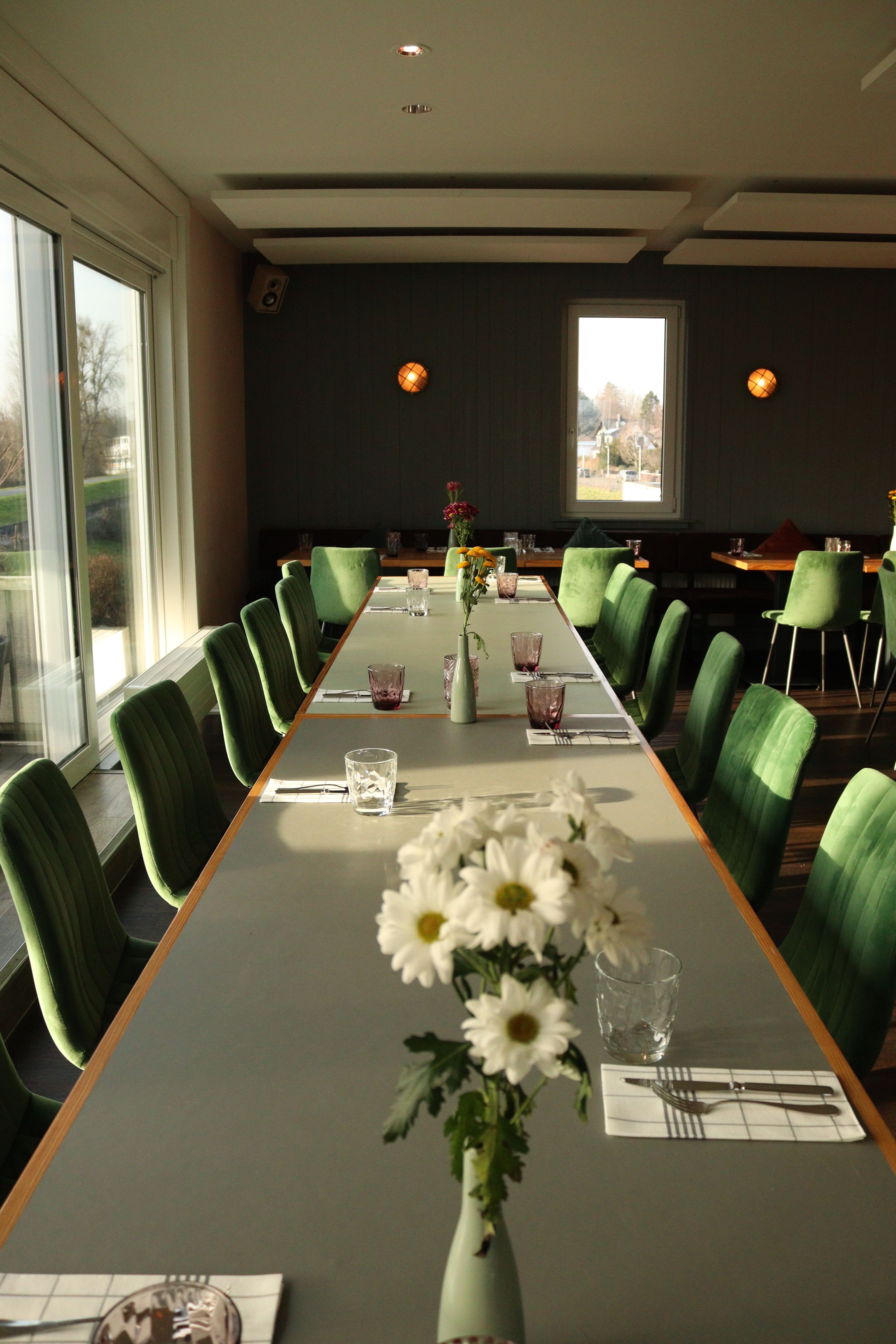 A stylish dining room setup with green chairs and daisy floral arrangements.
