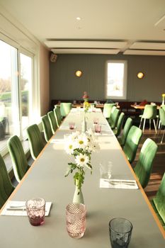 Stylish dining setup with green chairs and floral arrangements in a bright interior.