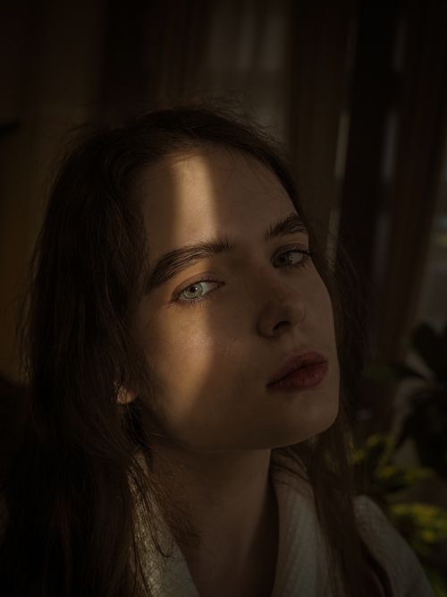 Free A dramatic portrait capturing a woman with sunlight shadows on her face, evoking a mysterious mood. Stock Photo