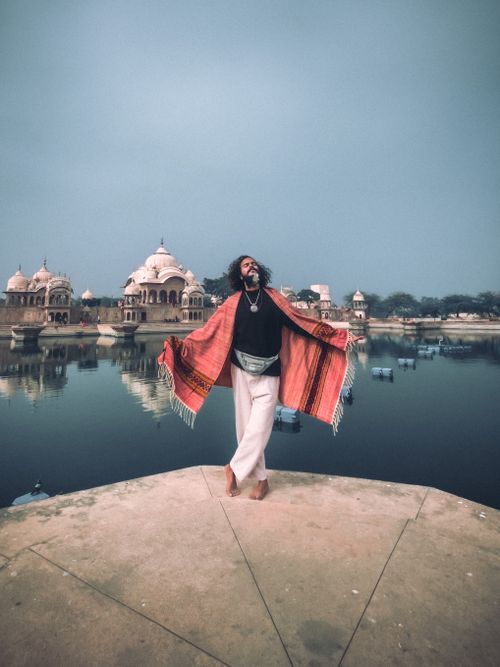 Free Man basking in spiritual freedom near Indian temple by tranquil waters. Stock Photo