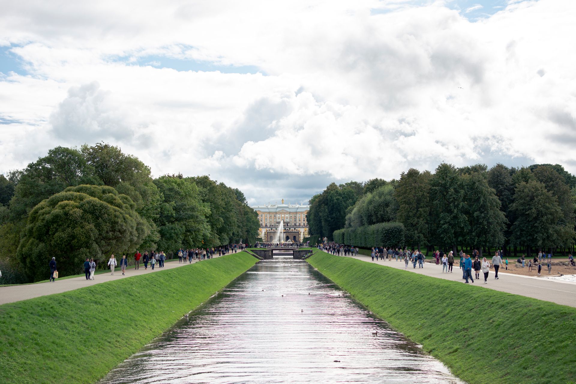 Beautiful park landscape with a canal and distant palace on a summer day.