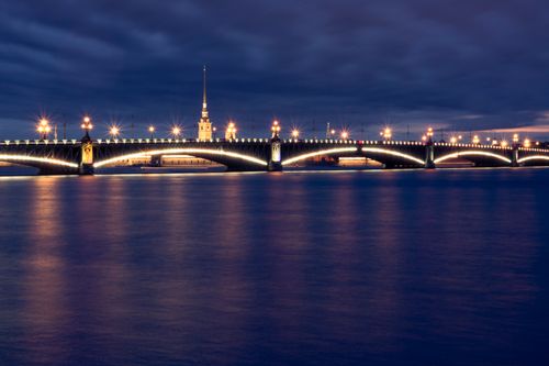 Free Scenic nighttime view of an illuminated urban bridge with reflections on calm water. Stock Photo
