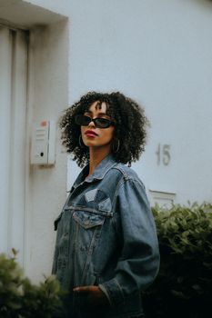 Fashionable woman in a jean jacket with sunglasses outdoors.