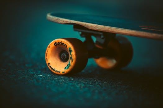 Artistic close-up of a skateboard with orange wheel on pavement.