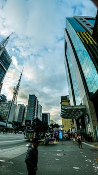 Fisheye view of urban cityscape with bustling streets and modern skyscrapers on a cloudy day.