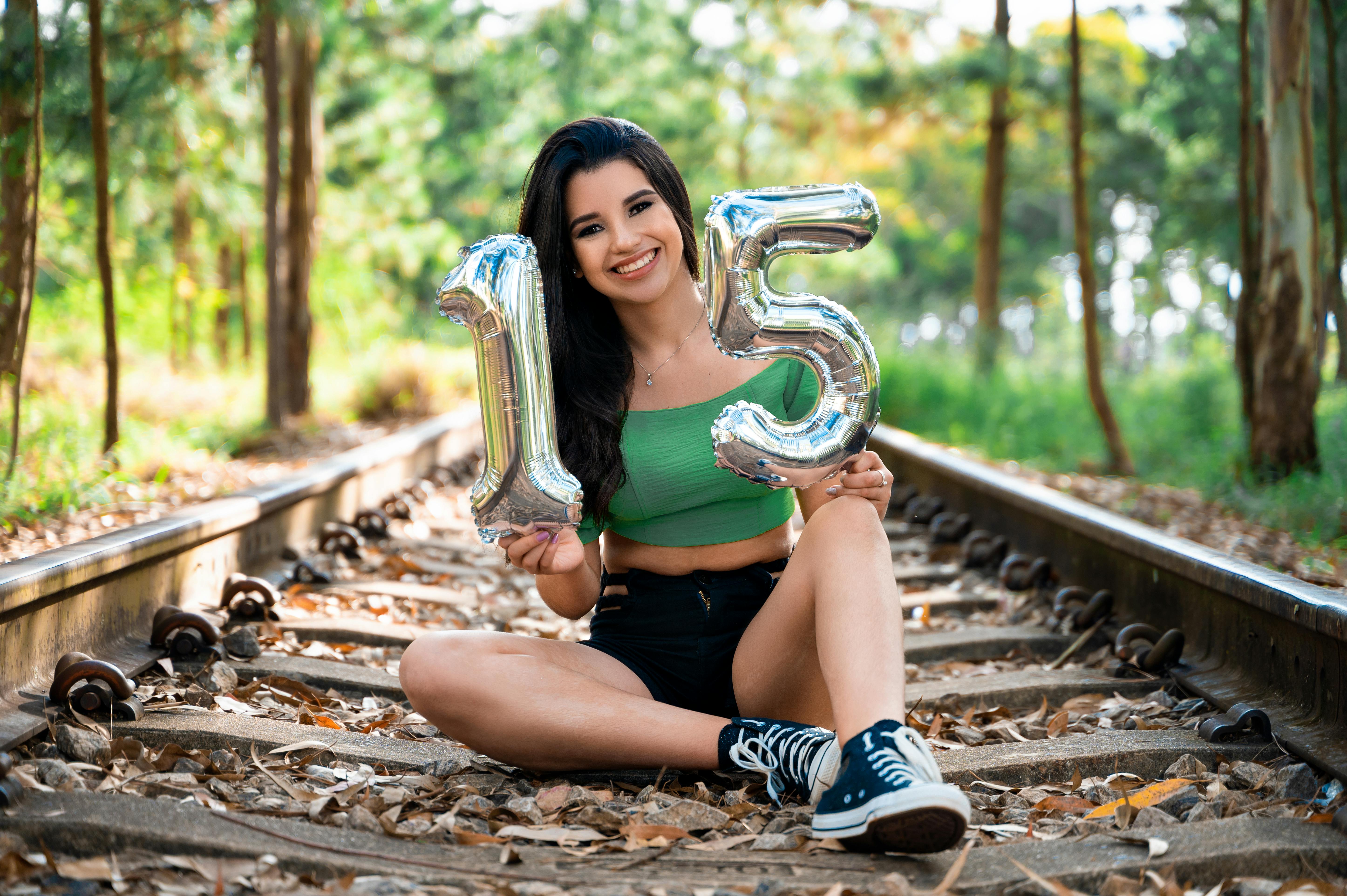 smiling girl with inflatable numbers sitting on railway tracks