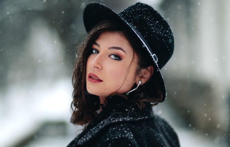 Posed Photo Of A Young Woman In A Black Hat Covered In Snow