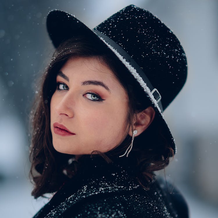 Posed Photo Of A Young Woman In A Black Hat Covered In Snow