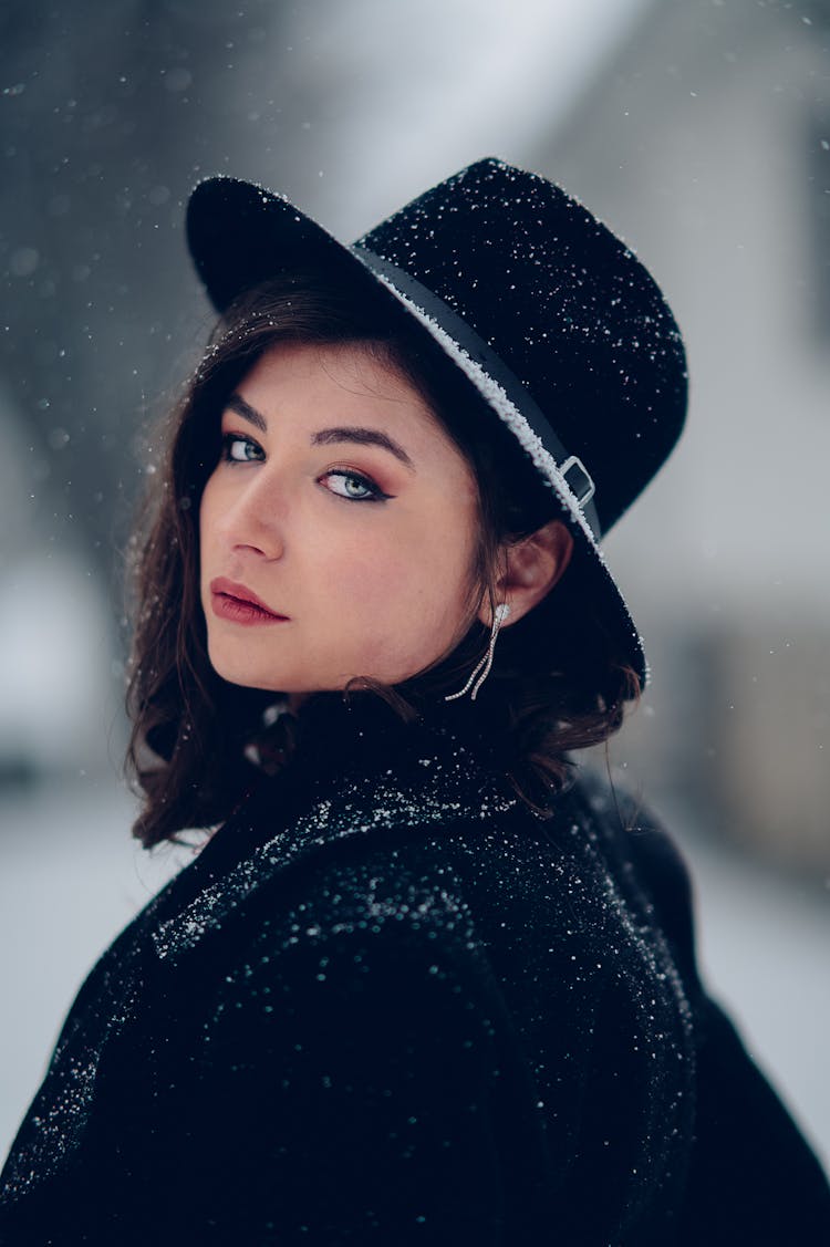 Posed Photo Of A Young Woman In A Black Hat Covered In Snow