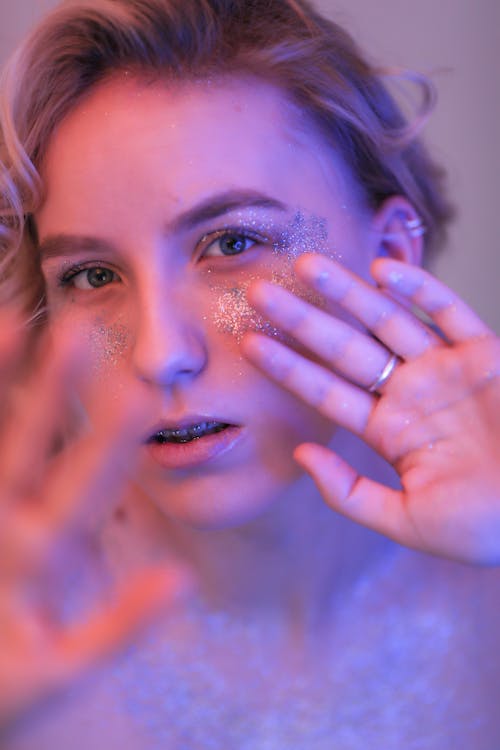 Young Woman with Glitters on Face in Pink Light