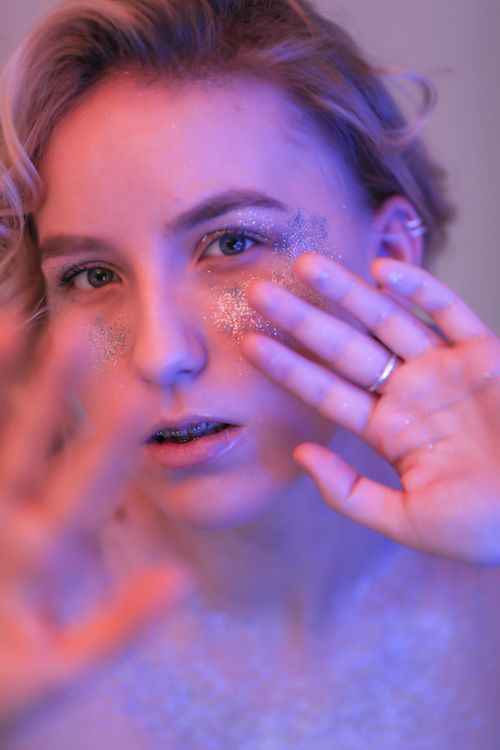 Free Intimate portrait of a young woman with glitter makeup in soft lighting. Stock Photo