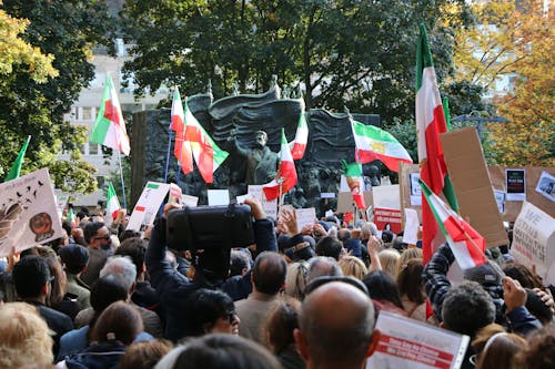 Crowd with Iranian Flags Standing by a Monument