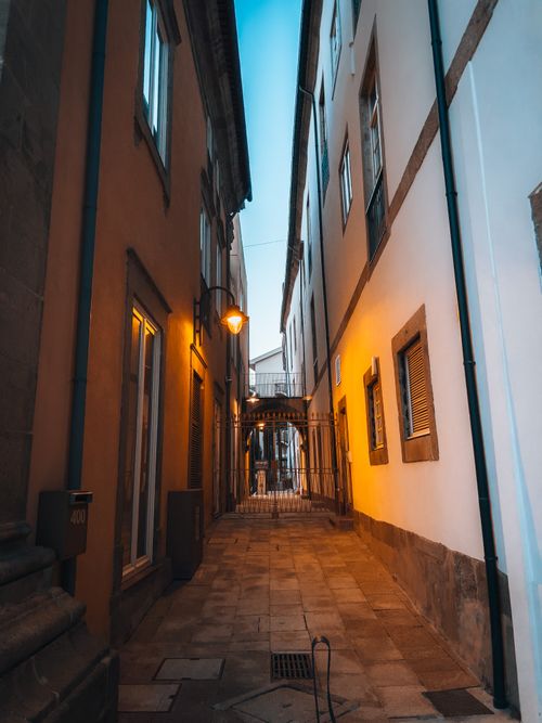 Free A narrow alley in an old town with warm street lights illuminating the cobblestone path. Stock Photo