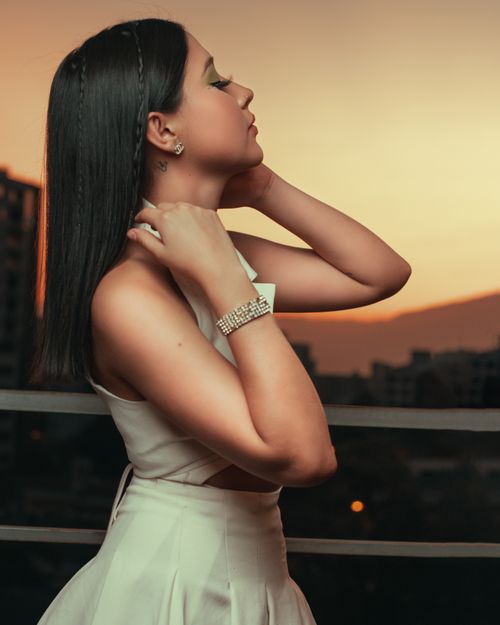 Free Side profile of a woman with black hair enjoying sunset outdoors, wearing elegant attire. Stock Photo